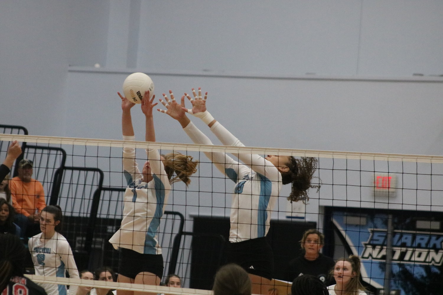 Ava Grall (No. 1) deflects a shot at the net with help from Zeta Washington.